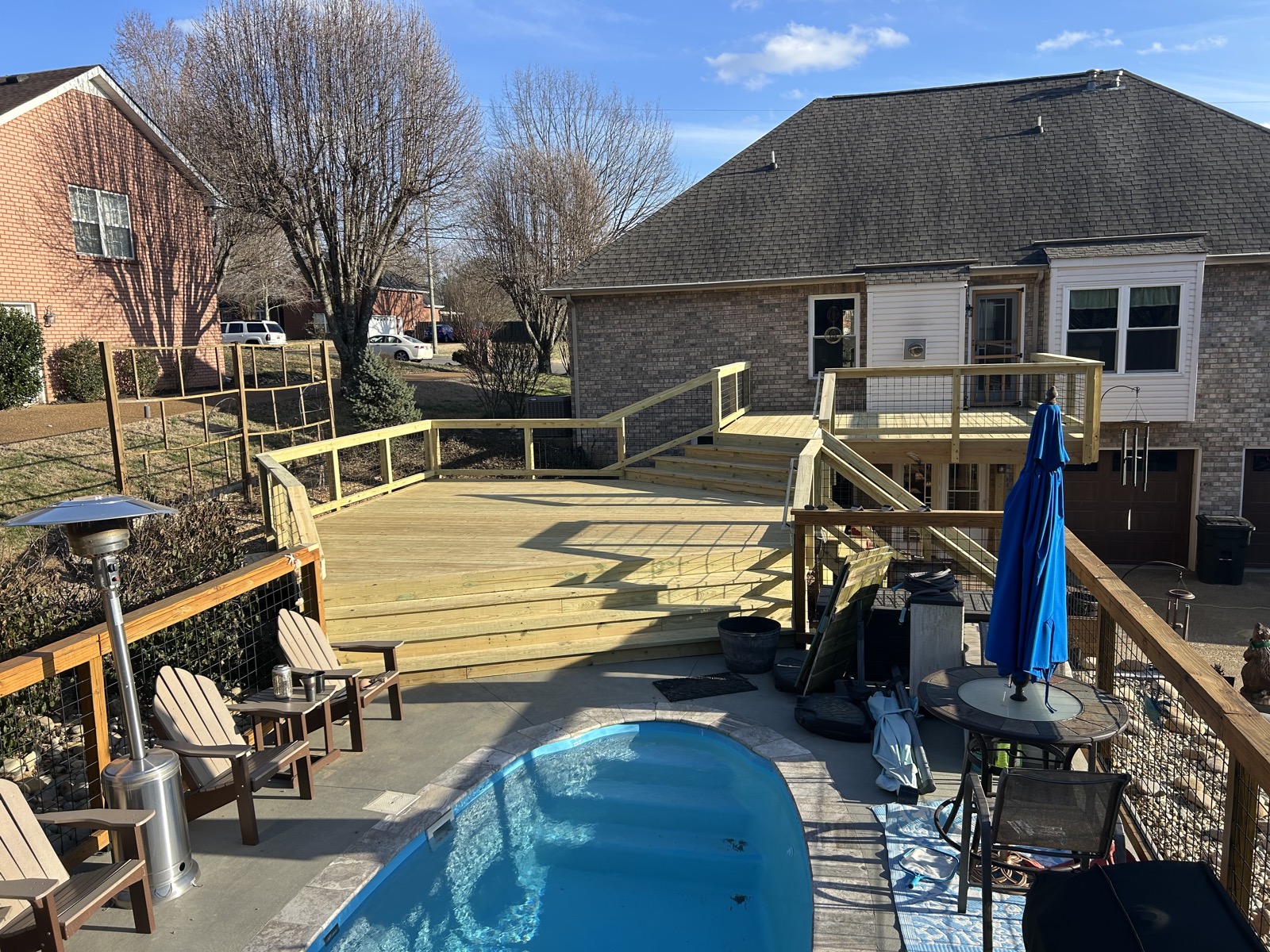 Multi-level wood deck wrapping a backyard pool with lounge seating