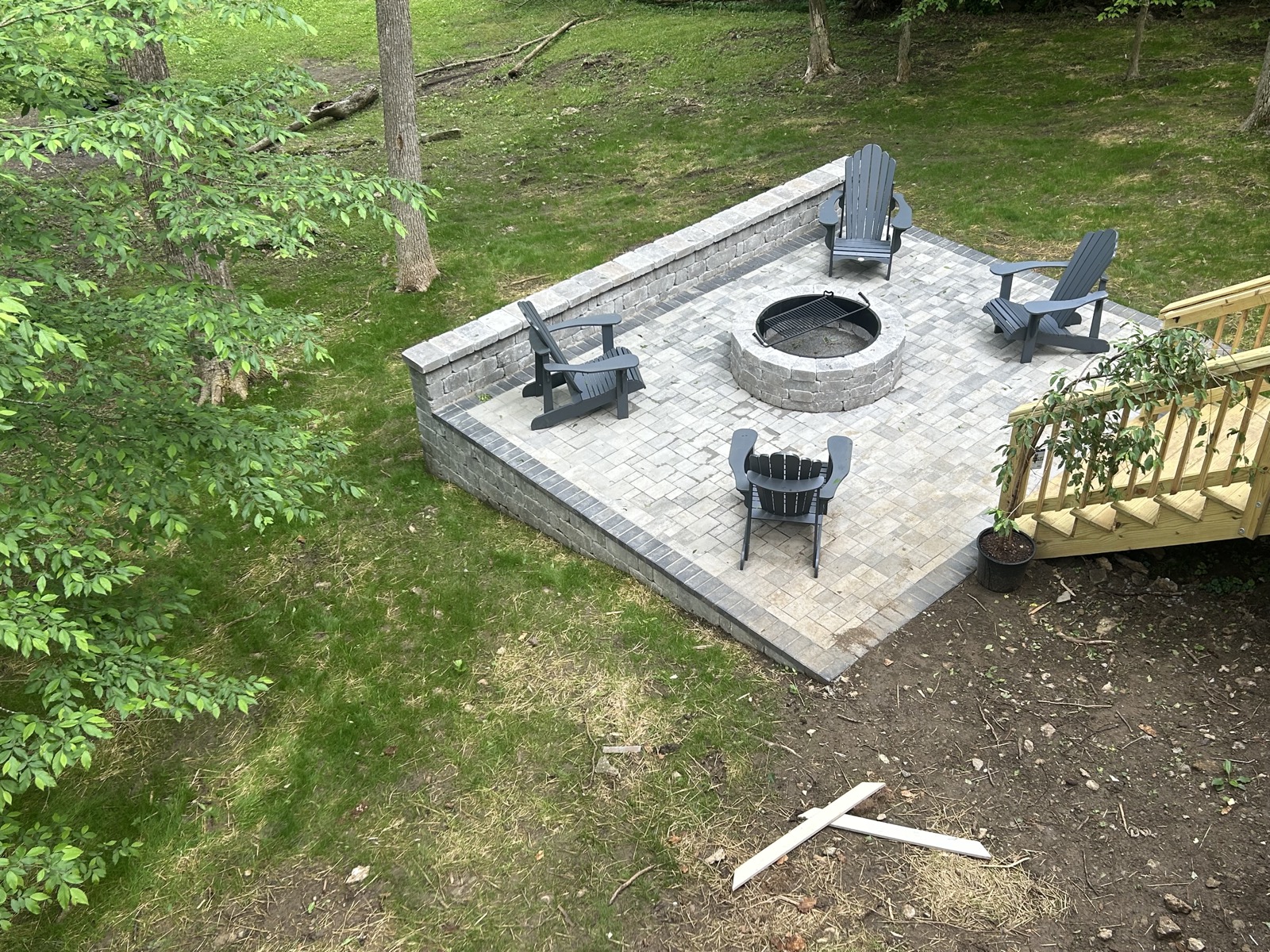 Stone fire pit set in a paver patio with Adirondack chairs