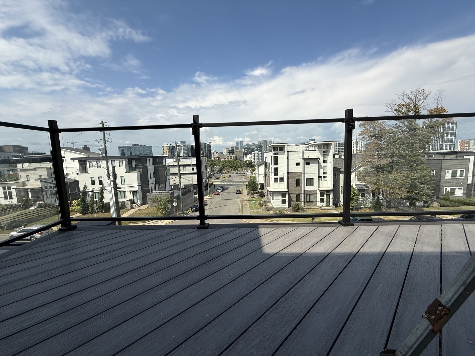 Rooftop composite deck with slim black-framed glass railing and skyline view