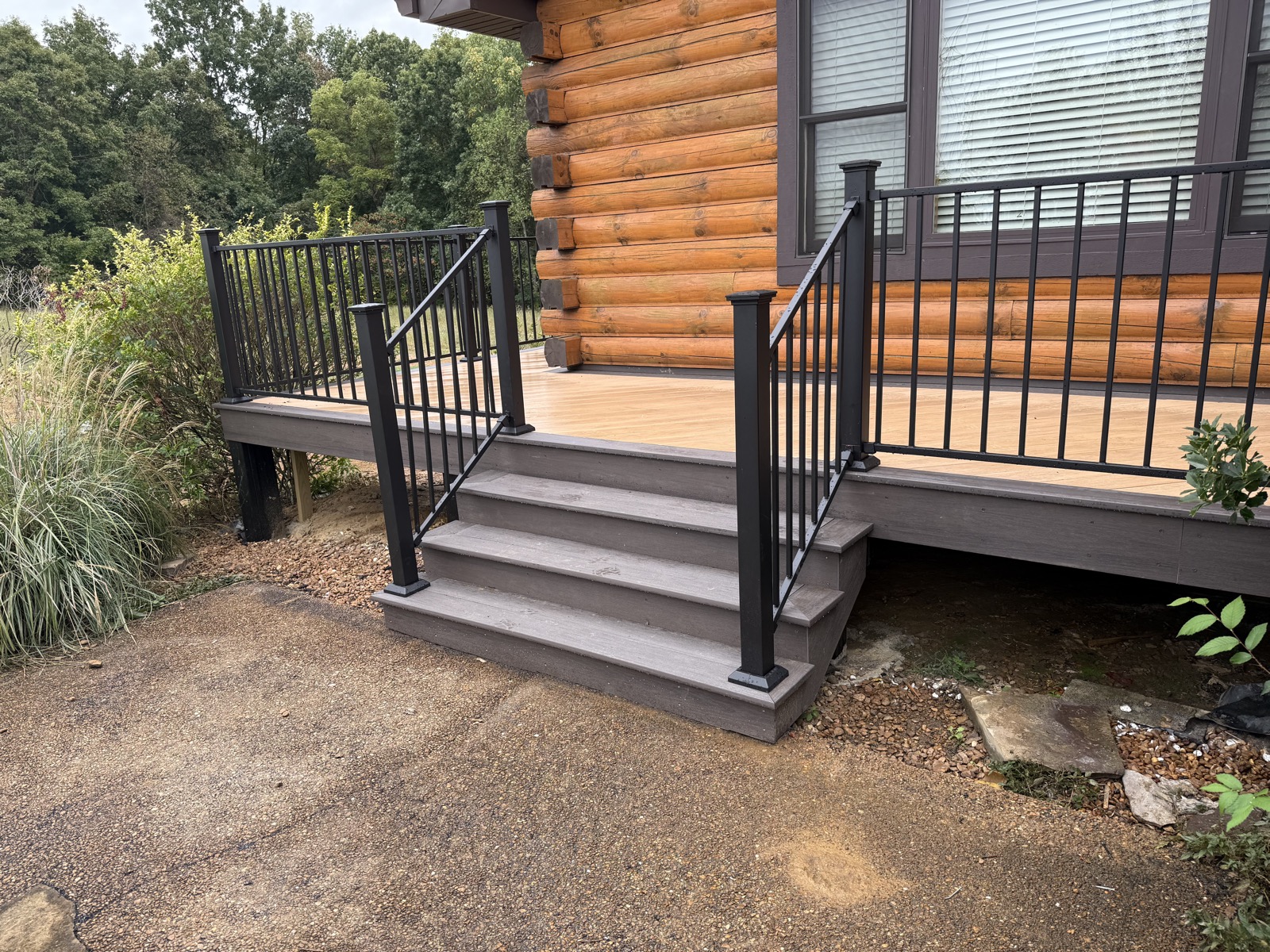 Composite deck steps with black aluminum railing at a log home