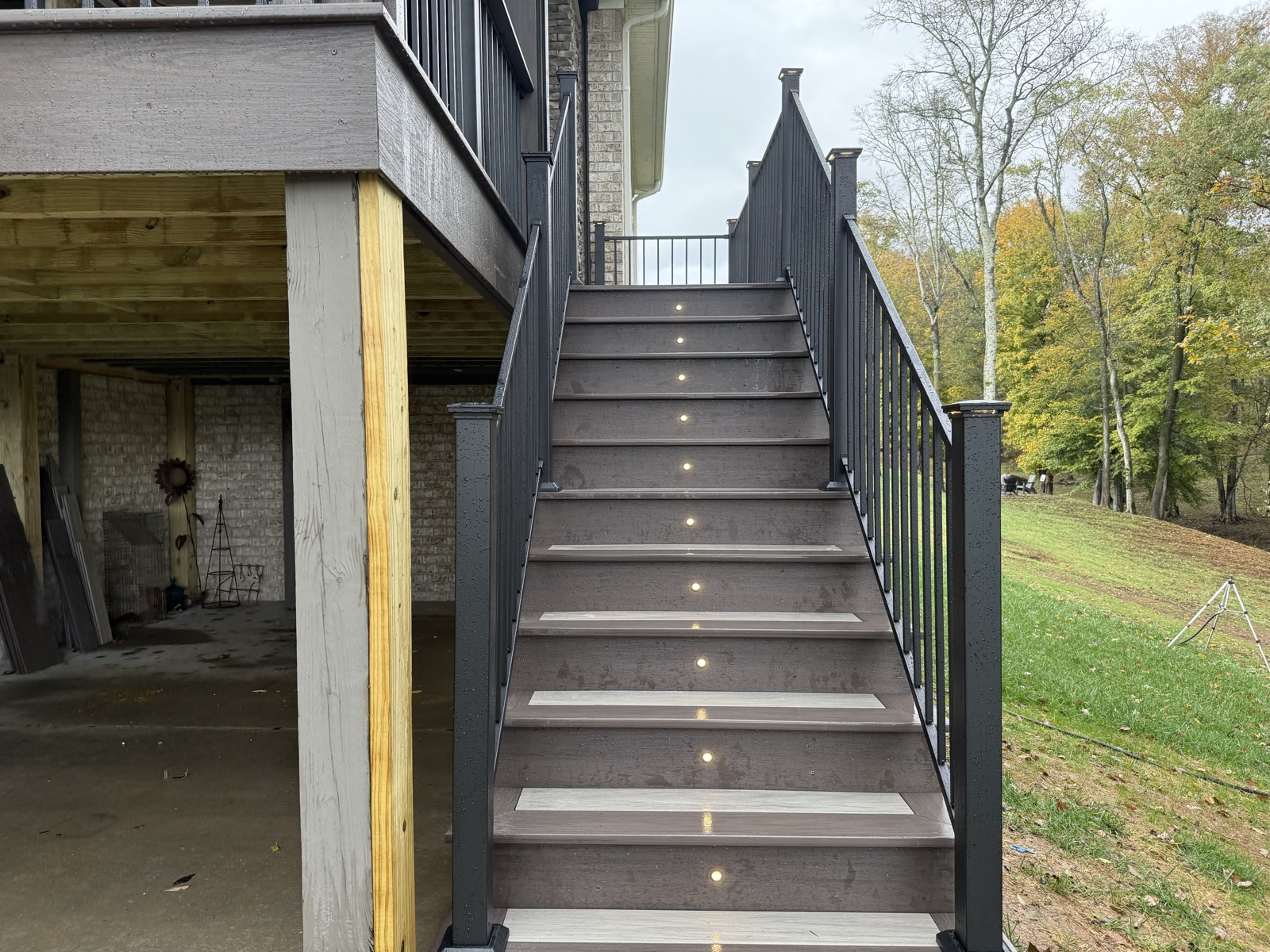 Composite stairs with lit risers and black aluminum railing at dusk