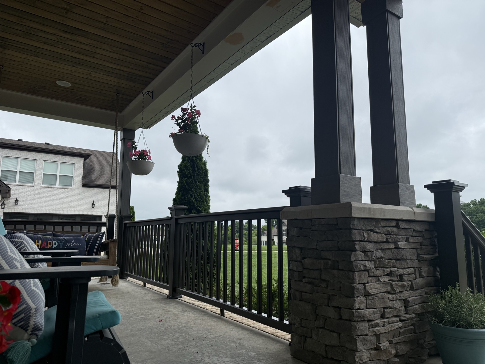 Covered porch with a stone column, porch swing and golf-course view